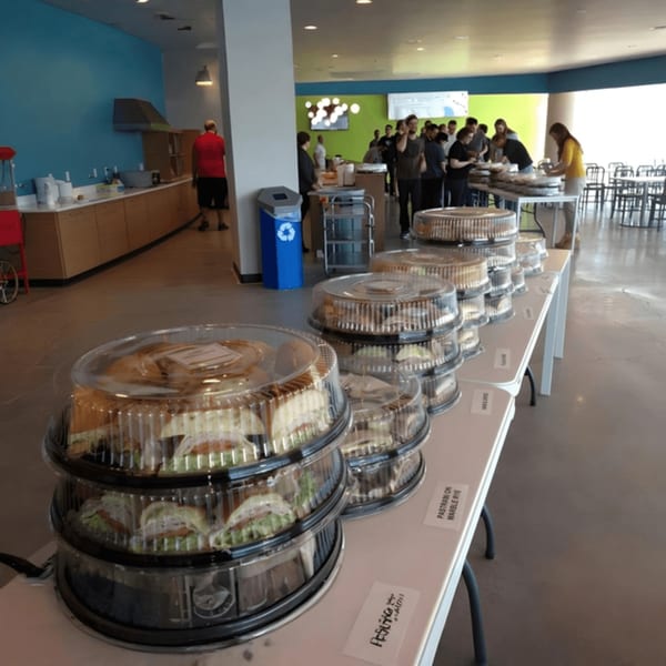 Knickerbockers Deli sandwiches in plastic containers on tables, with people in the background.