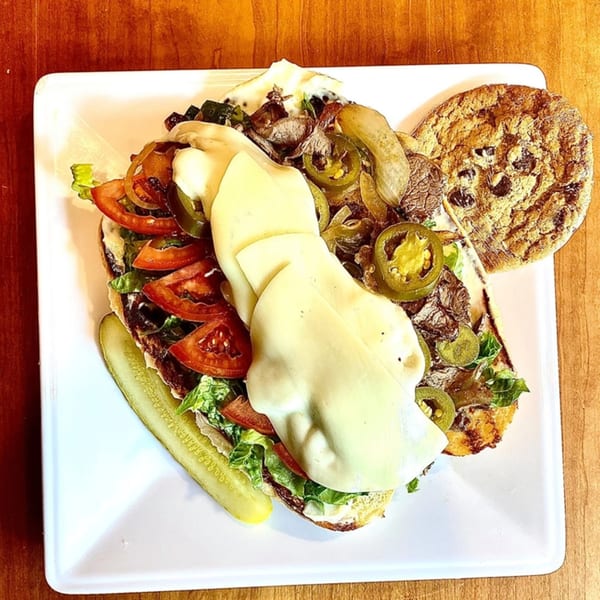 Knickerbockers Deli sandwich with steak, cheese, lettuce, tomatoes, jalapenos, and a pickle, with a cookie.